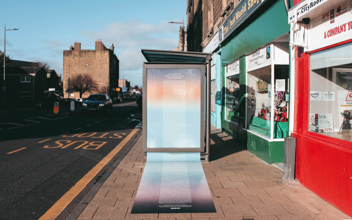 Image of an ad campaign at a bus stop, with the poster and its text spilling down beyond the bottom of the poster frame and on to the pavement.